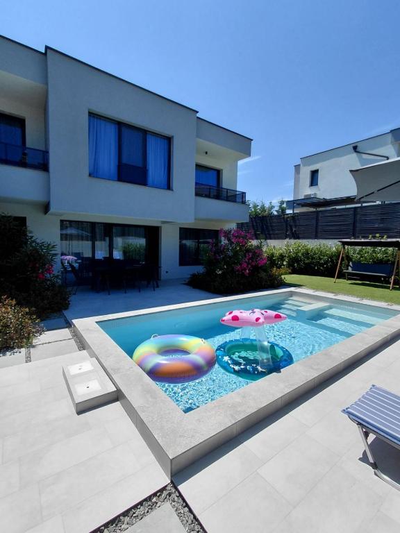 a swimming pool with an umbrella and two inflatables at Villa Felicity, private pool with heating and salt water in Lozenets