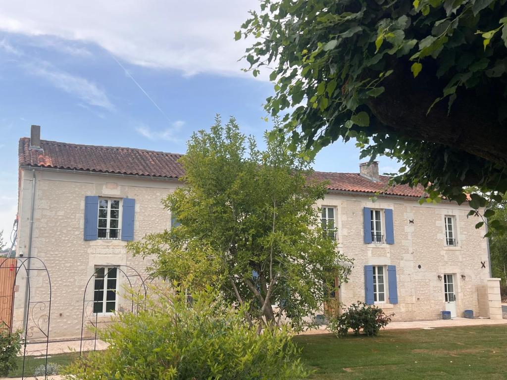 a large brick building with blue windows and a tree at Hôtel Le Groom in Laprade
