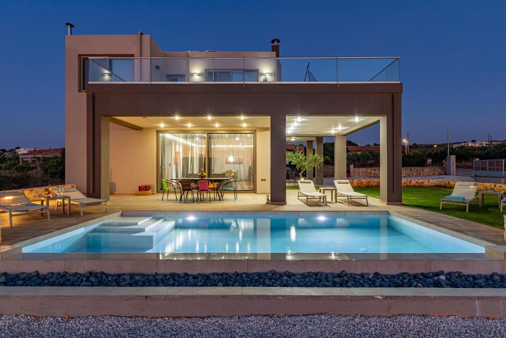 a villa with a swimming pool in front of a house at GOLD DREAM HOME in Agios Onoufrios