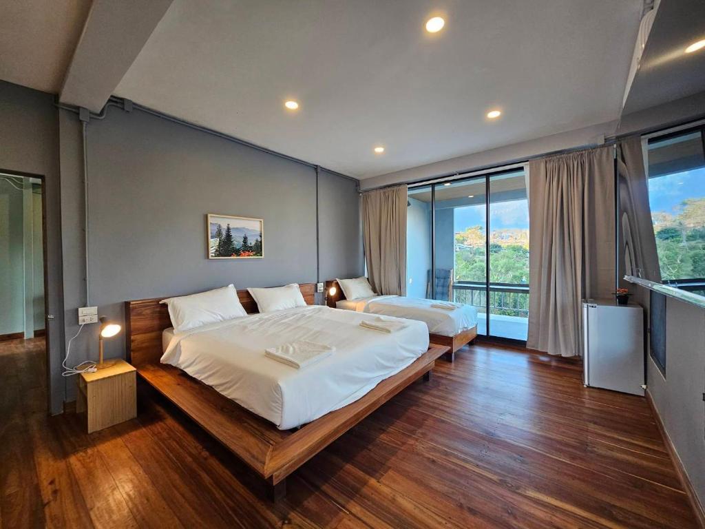 a bedroom with two beds and a large window at Piney Stay ไพนี่สเตย์ เขาค้อ in Campson