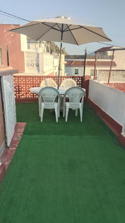 two chairs and a table with an umbrella on a roof at Casa JUANES in Cullera