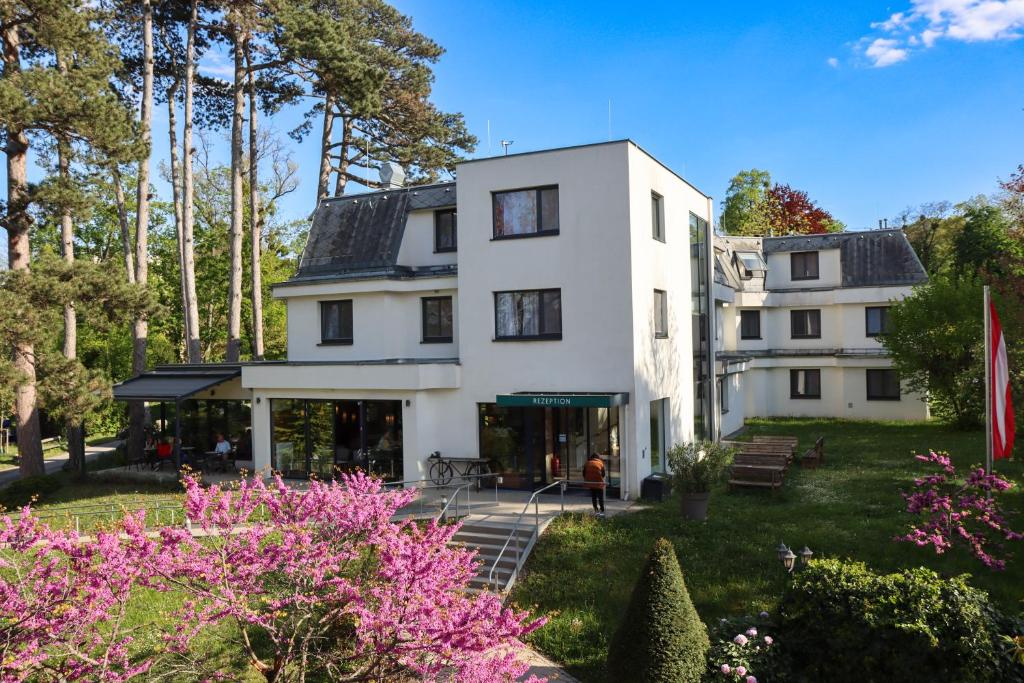 a white house with trees and pink flowers at Seminarhotel Springer Schlössl in Vienna