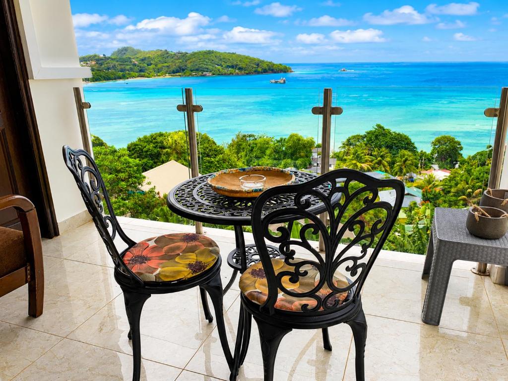 a table and chairs with a view of the ocean at Sunset View Self Catering in Anse Boileau