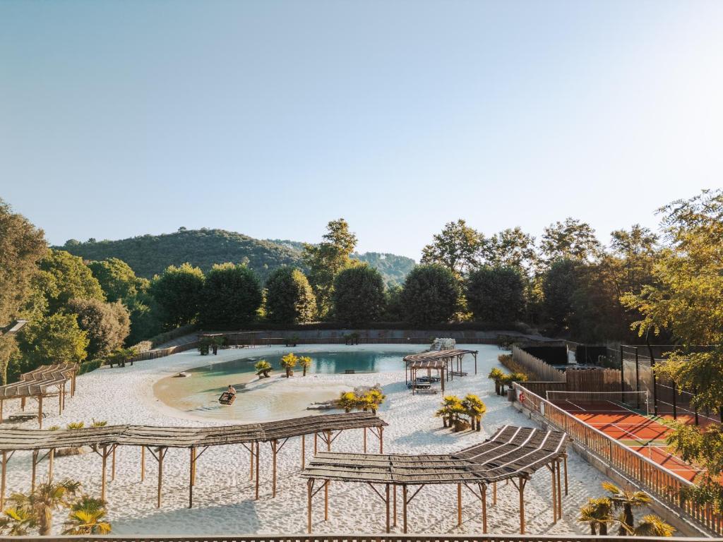 a pool with tables and benches in a park at Camping la Clémentine in Cendras