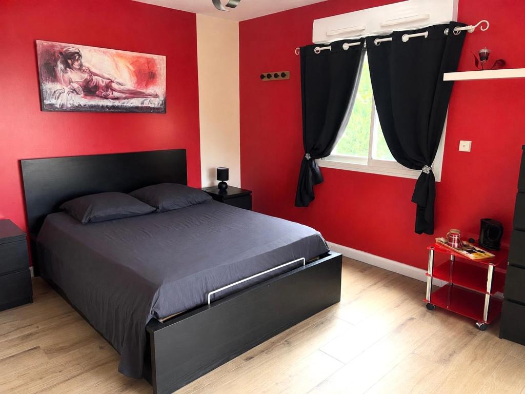 ein Schlafzimmer mit roten Wänden, einem Bett und einem Fenster in der Unterkunft La Villa des Demoiselles - 2 chambres communicantes in Bourg-Achard