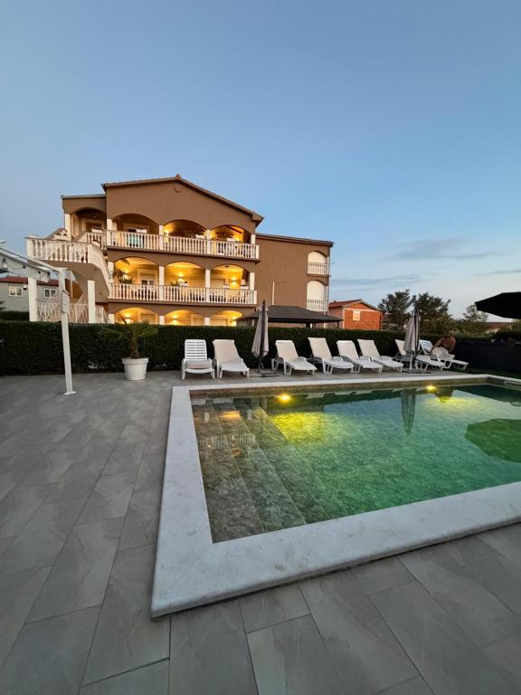 a swimming pool with lounge chairs and a building at Apartmani Anđelo, Tommy, Leon in Bibinje