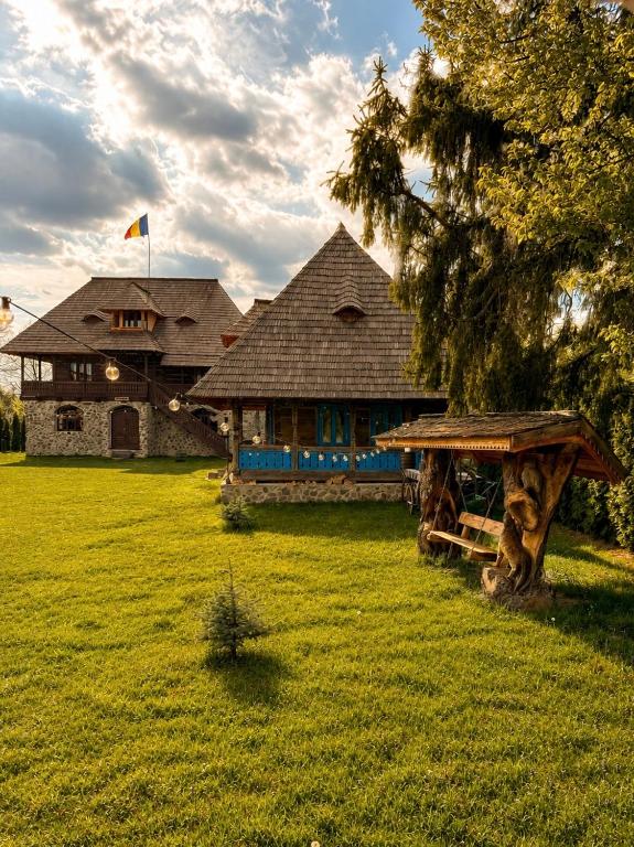 a large log house with a flag on top of it at La Patru Daci in Ocna Şugatag