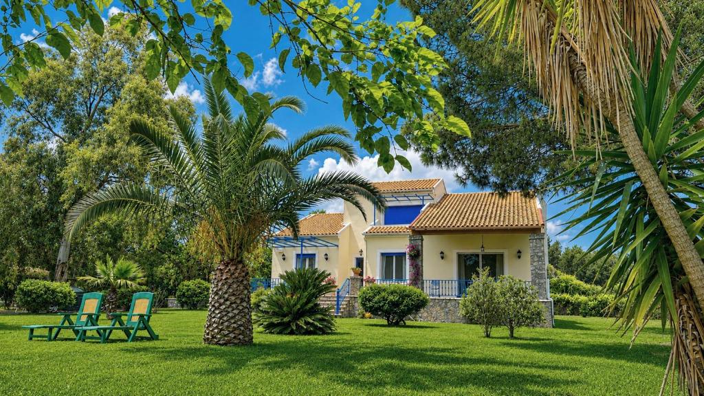 a house with palm trees and chairs in the yard at Villa Lefka Stunning Seaside Villa in Corfu with Private Gardens in Melíkia