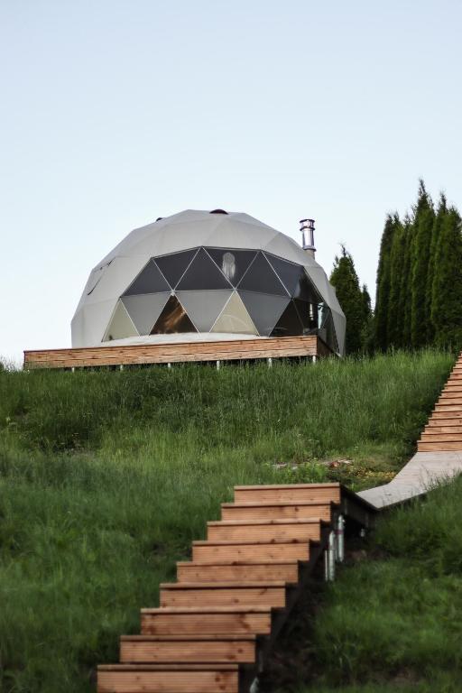 a building with a dome on top of a field at Glempingosta in Bauska
