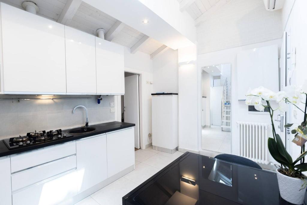 a kitchen with white cabinets and a black counter top at Asinelli, Bologna by Short Holidays in Bologna