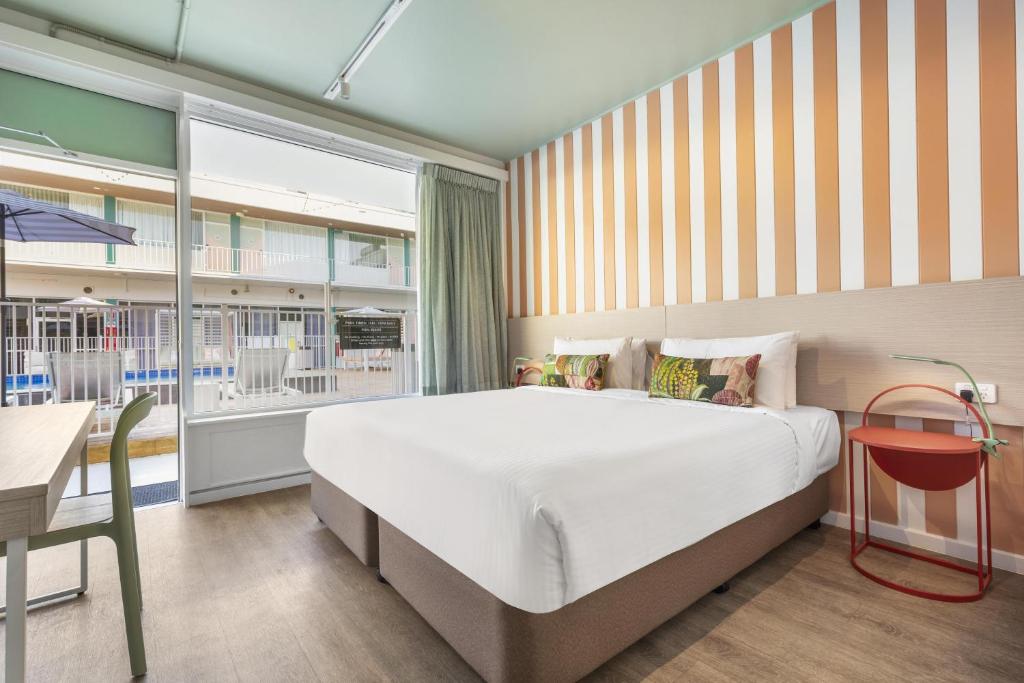 a bedroom with a large bed and a desk and a window at Nightcap at the Cavenagh in Darwin