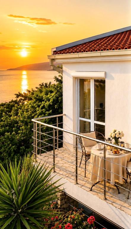 a house with a balcony with a sunset in the background at Villa Radis in Dobra Voda