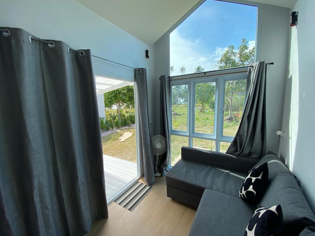 a living room with a couch and a sliding glass door at Beach Access Tiny House 06 - Lipa Noi Beach in Koh Samui