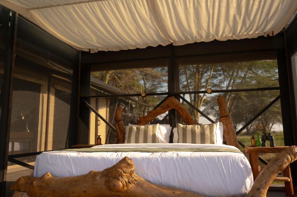 a bed in a room with a large window at Soroi Amboseli in Amboseli
