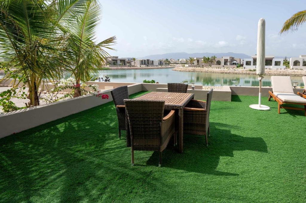 a table and chairs on a lawn with a view of the water at Luxury Salalah Villa in Salalah