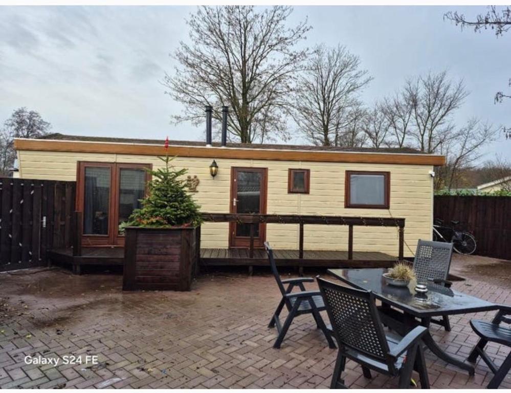 a tiny house on a patio with a table and chairs at Chalet te huur op Camping de Kleine Wielen te Leeuwarden in Leeuwarden