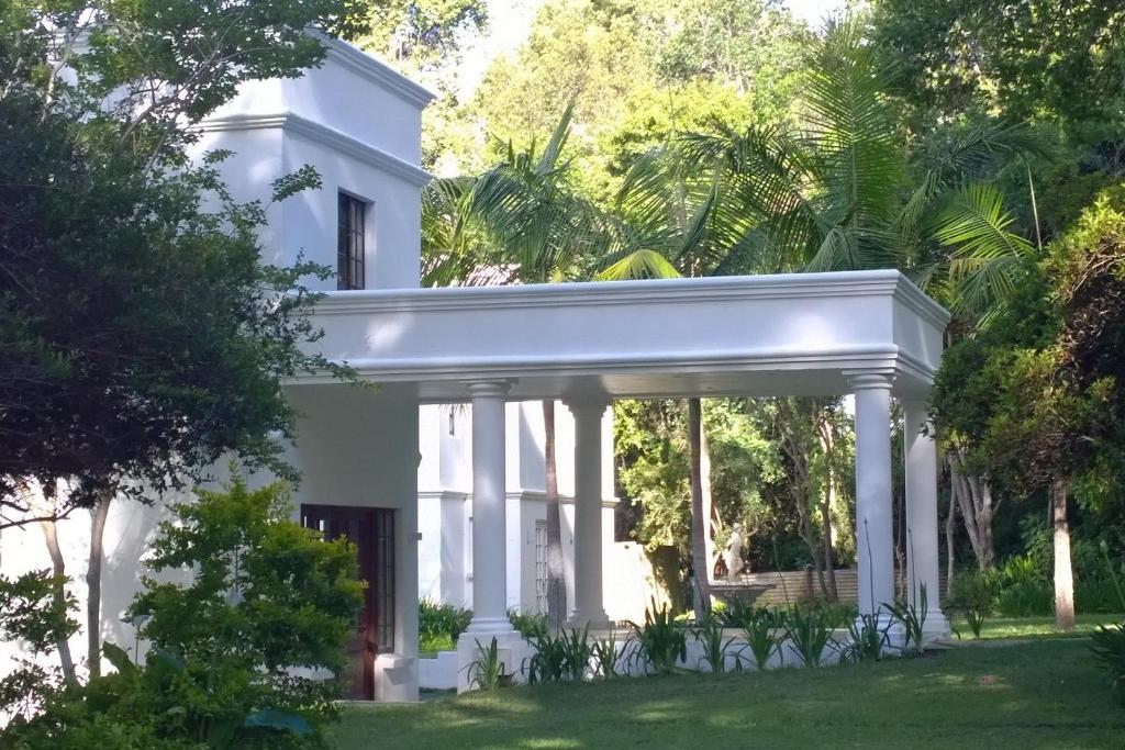 a white house with trees in front of it at Edenbrook Country Manor in Plettenberg Bay