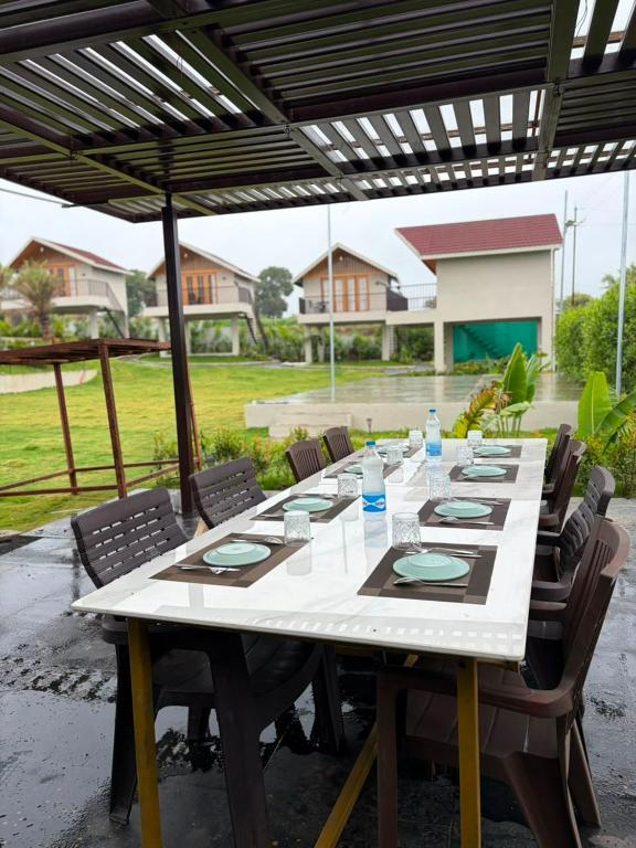 a long table with chairs and an umbrella at Dream Habitat in Wādhiware