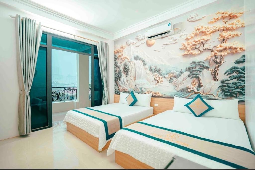 a bedroom with two beds and a painting on the wall at Chinh Thuỷ Hotel in Sầm Sơn