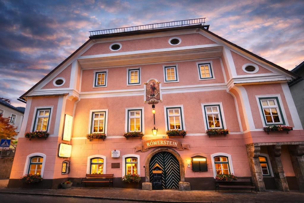 a large pink building with a clock on it at Hotel und Restaurant Römerstein in Bad Aussee