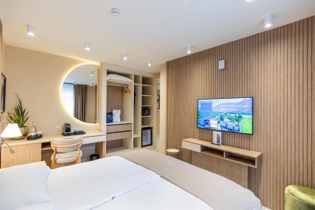 a hotel room with a bed and a tv on a wall at Villa Delta - Parkhotel Delta in Ascona