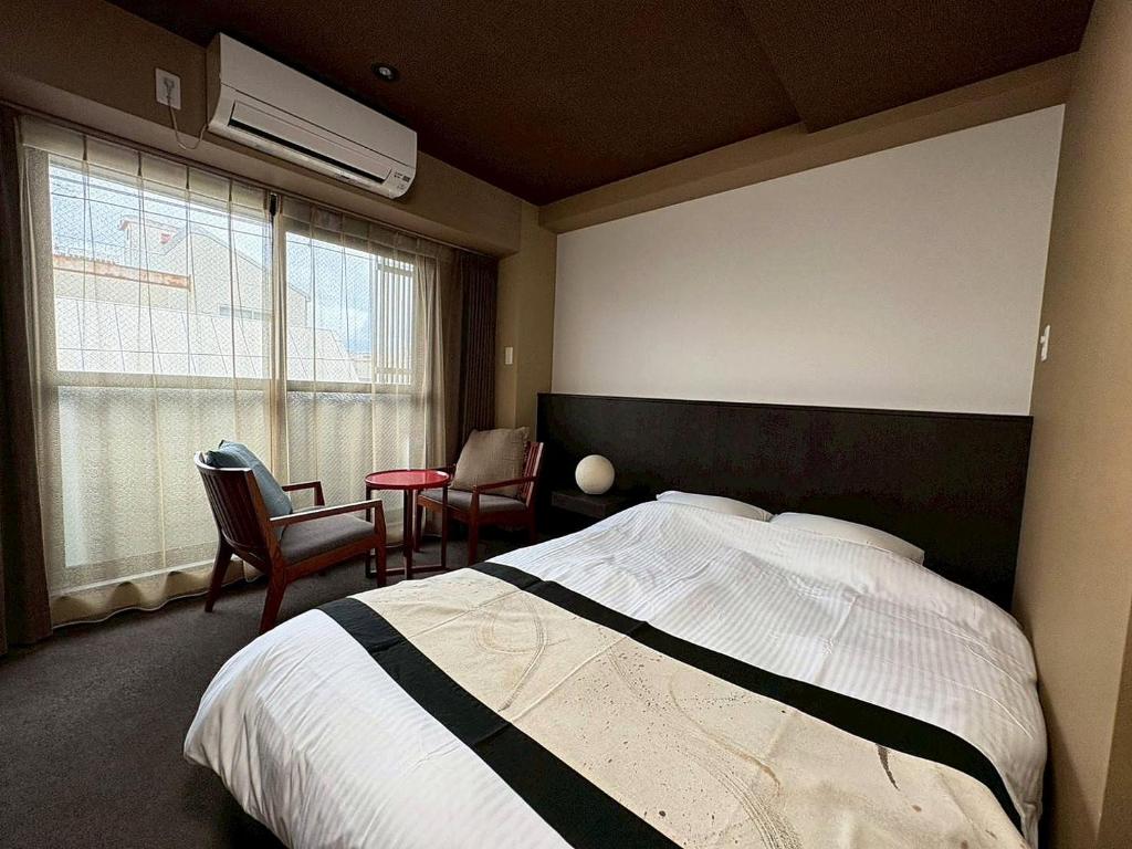 a bedroom with a bed and chairs and a window at ITOSHI Kyoto Stay 京都天神401 in Kyoto