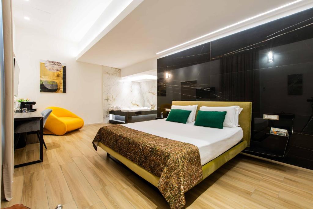 a bedroom with a large bed with a desk and a yellow chair at Municipio Luxury Suite in Naples