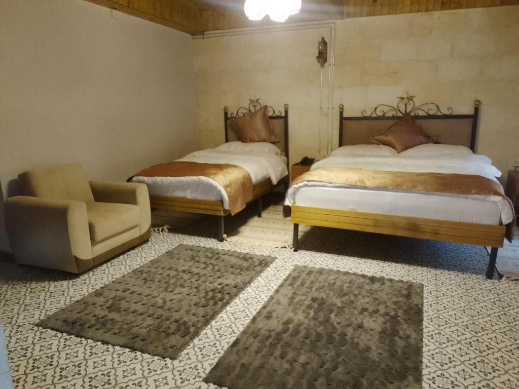 two beds in a room with a chair and a couch at Hurşit Bey Konağı in Gaziantep
