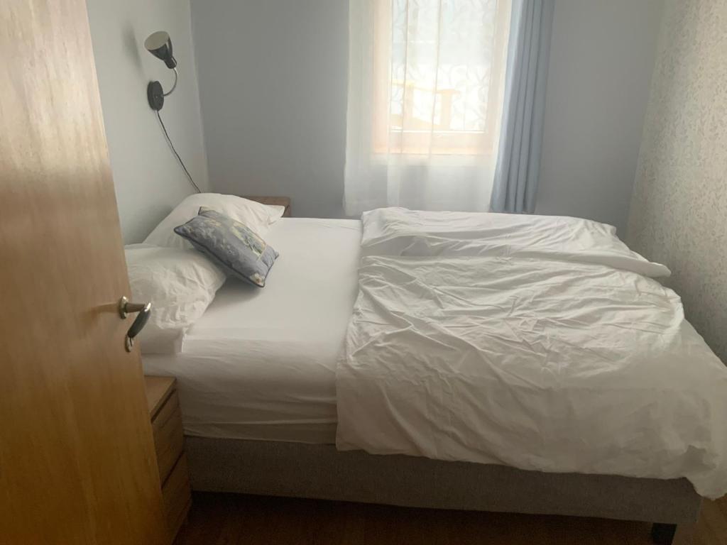 a bedroom with a bed with white sheets and a window at Ørntua in Rekdal