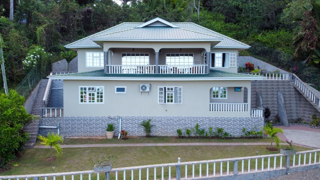 a white house with a fence in front of it at Exotic Guest House in Praslin