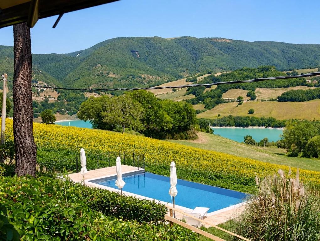 a swimming pool with a view of a river and mountains at La Corte Sul Lago in Cingoli