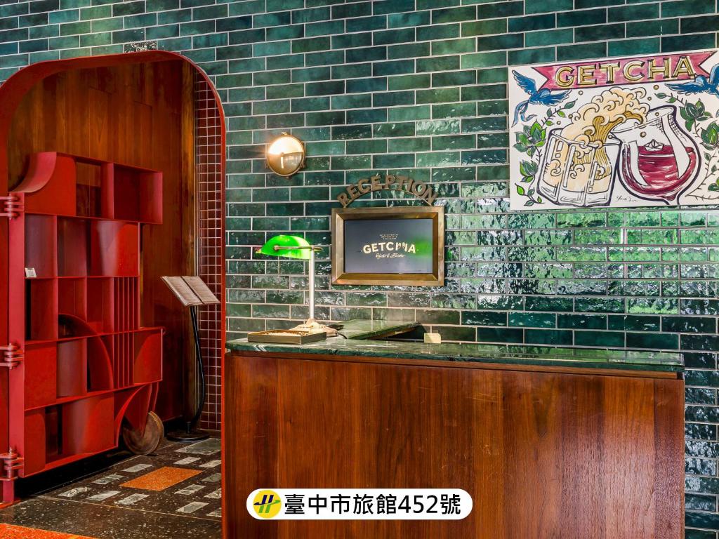 a restaurant with a counter with a tv on a brick wall at Getcha Hostel in Taichung
