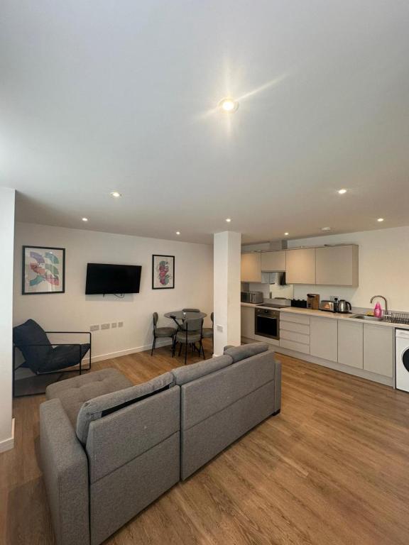 a living room with a couch and a kitchen at The Apollo Apartments in Saint Neots