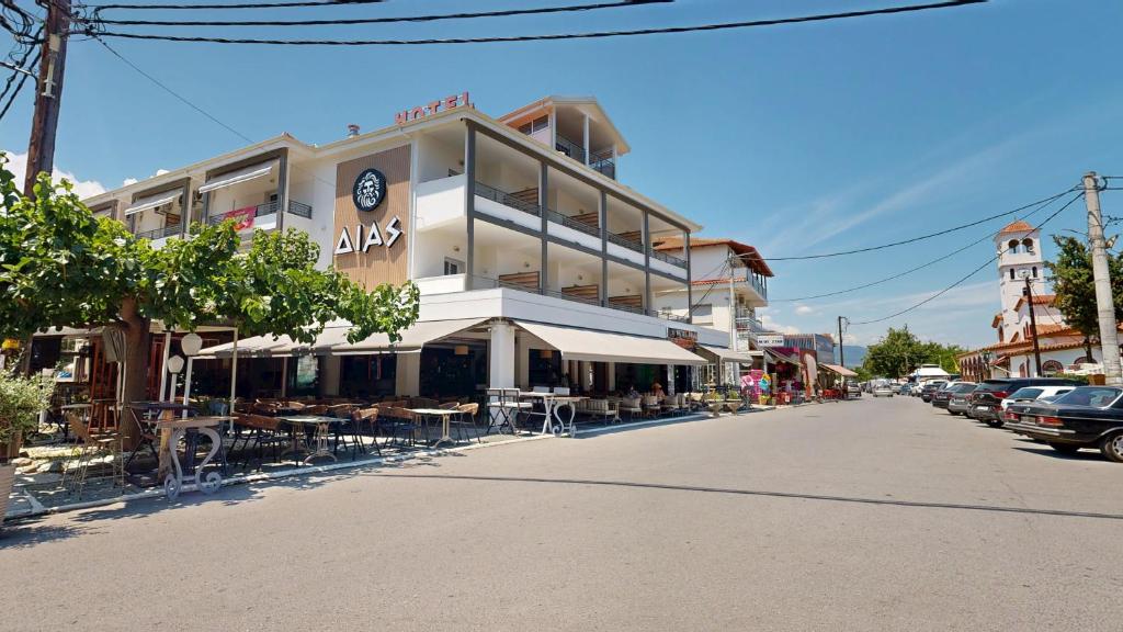 a building on a street with tables and chairs at Dias Hotel Platamon in Platamonas