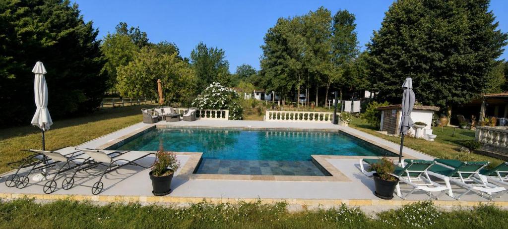 a swimming pool with chairs and umbrellas at Gîte Maelga in Cartelègue
