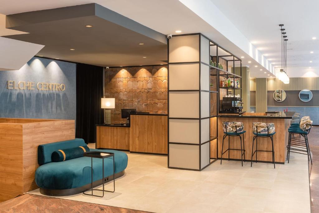 a lobby with a blue chair and a bar at Hotel Elche Centro, Affiliated by Meliá in Elche