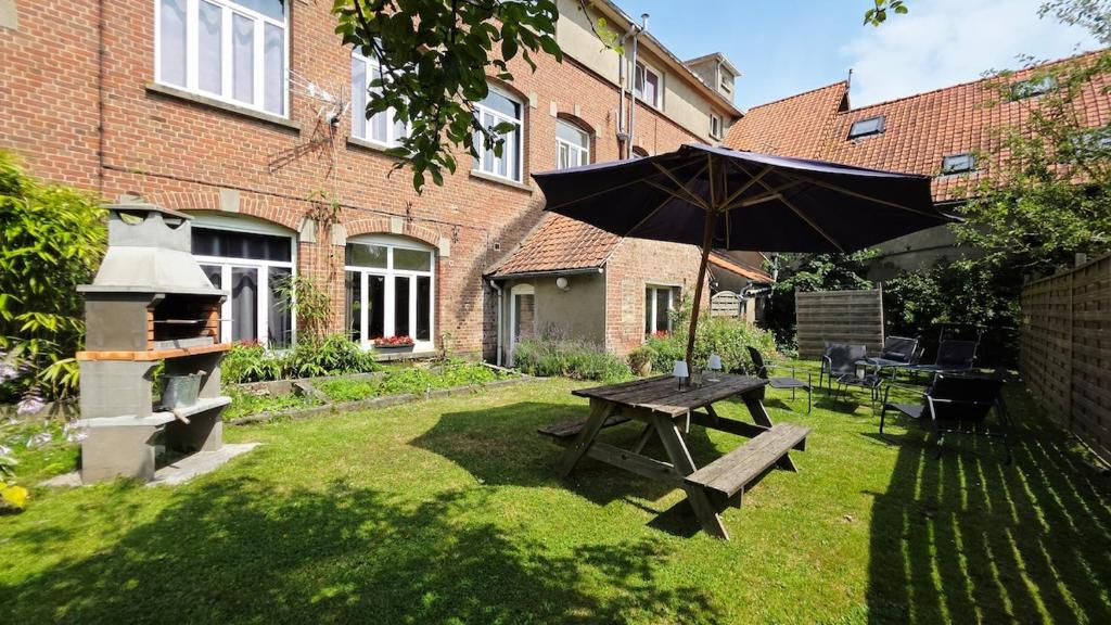 a picnic table with an umbrella in a yard at Domaine Les Tourelles - Gîte 2 in Caffiers