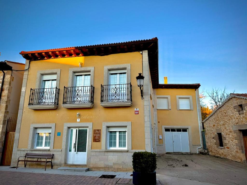 a yellow building with balconies and a bench in front of it at El abrazo de La Yecla in Espinosa de Cervera