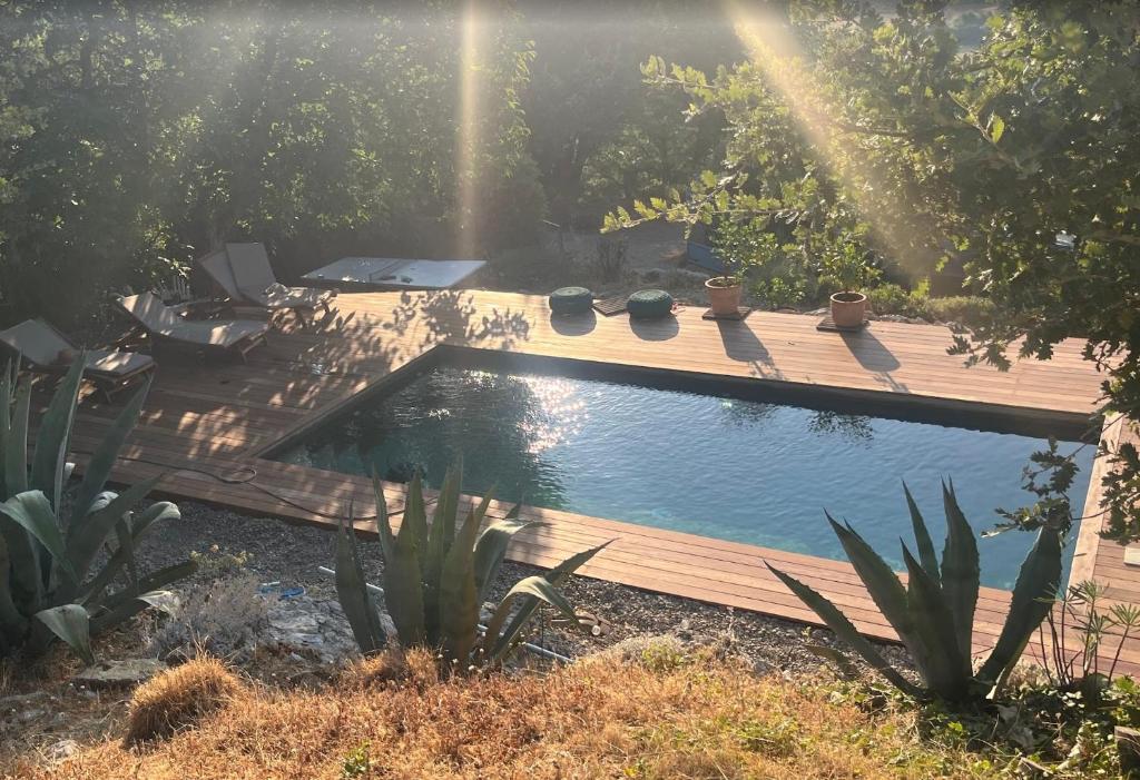a swimming pool in a garden with a wooden deck at La Traversière Condorcet in Condorcet