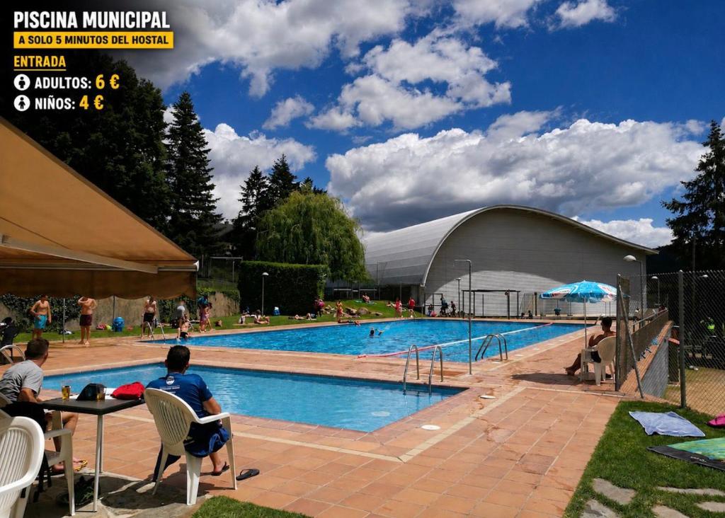 a man sitting at a table in front of a swimming pool at Cubez Viladrau by Dynamic Hotels in Viladrau