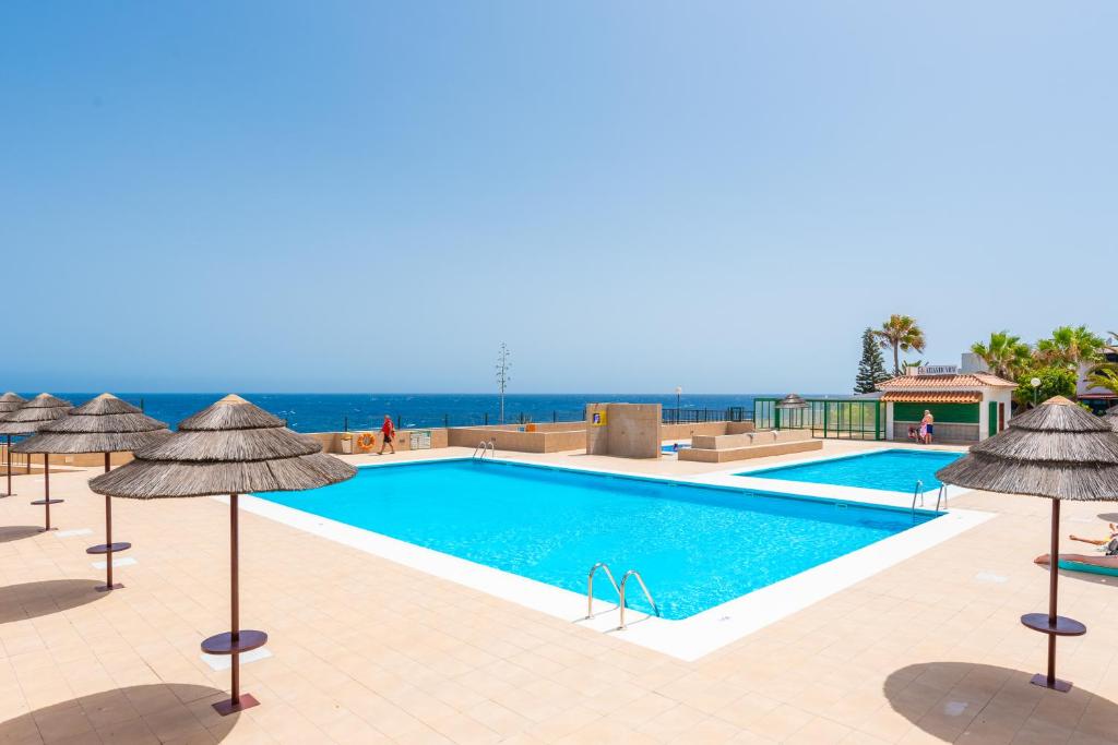 a swimming pool with umbrellas and the ocean at Atlantic Penthouse Retreat in Costa Del Silencio