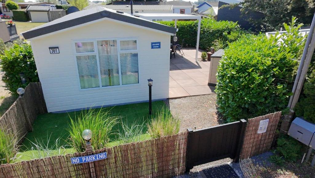 a small white house in a yard with a fence at Chalet SEASIDE in Lathum