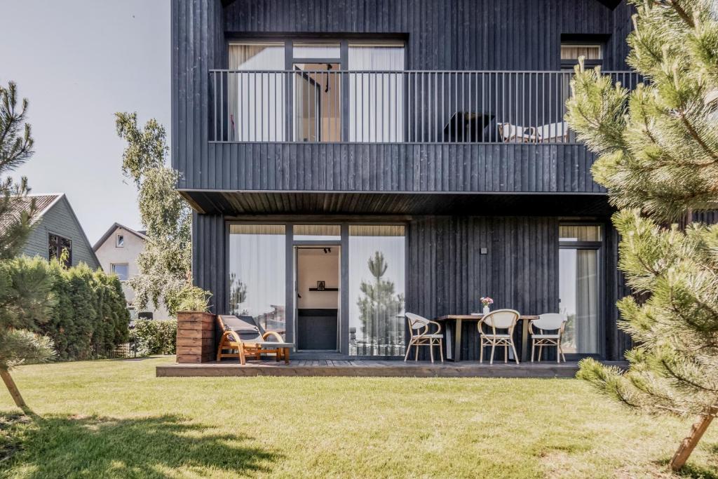 a black house with a balcony and a table at Topolių terasos in Palanga