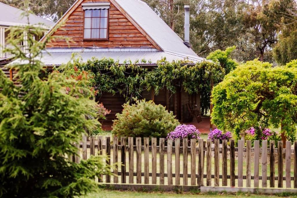 a wooden fence in front of a house with flowers at The Cottage at Paramoor Winery in Carlsruhe
