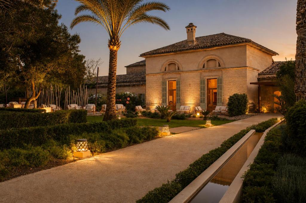 a house with a palm tree and a pathway at Fontsanta Hotel Thermal & Spa - Adults Only in Colònia de Sant Jordi