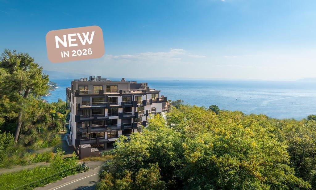 a view of a building with the ocean in the background at Aminess Younique Vollo Hotel Residences in Opatija