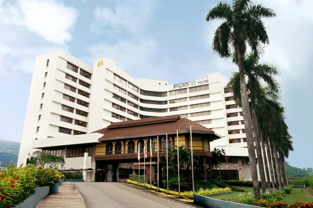 a hotel with a palm tree and a building at Impiana Hotel Ipoh in Ipoh