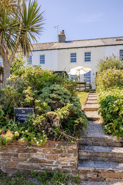 a white building with a palm tree and stairs at 2a Coastguard Cottages in Gorran Haven