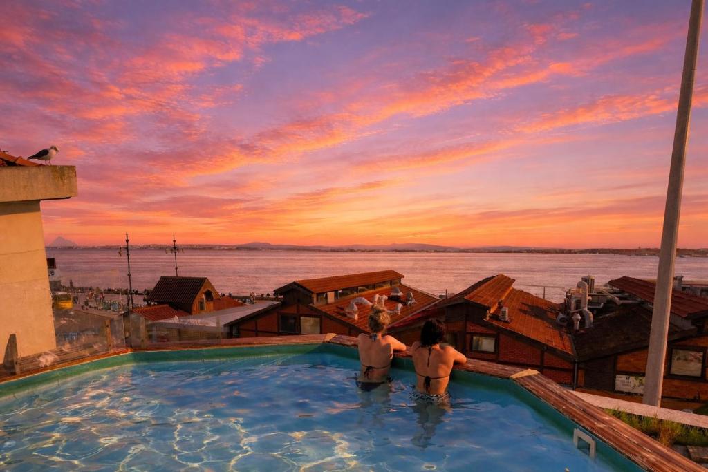 two people standing in a swimming pool at sunset at Sunset Destination Hostel in Lisbon