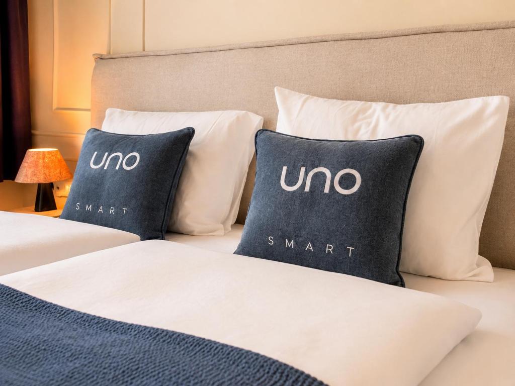 a bed with two pillows with the word omega on it at UNO Smart Hamburg Central 056 in Hamburg